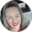 Smiling woman with vibrant red lipstick and wavy hair.